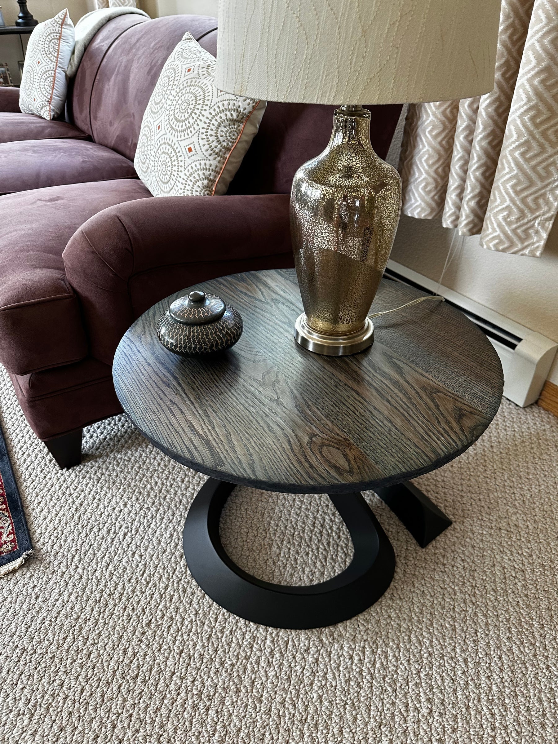 Finished round indigo white oak end table beside a chair