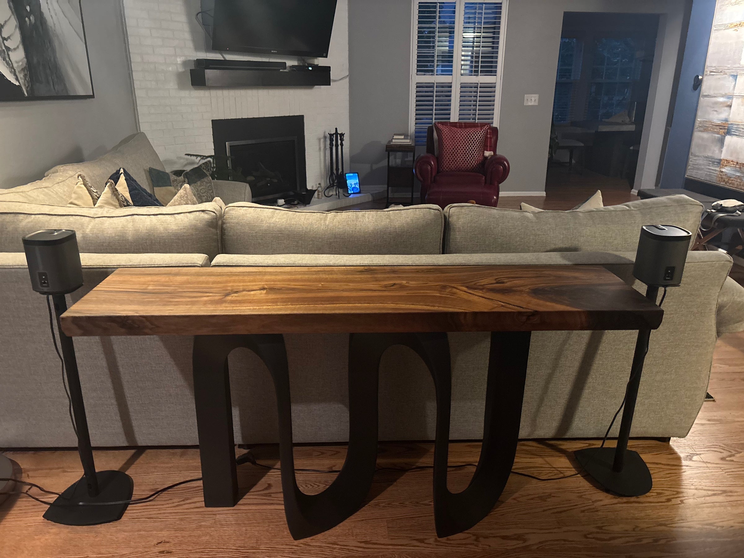 Finished black walnut console with sculptural black base behind a sofa
